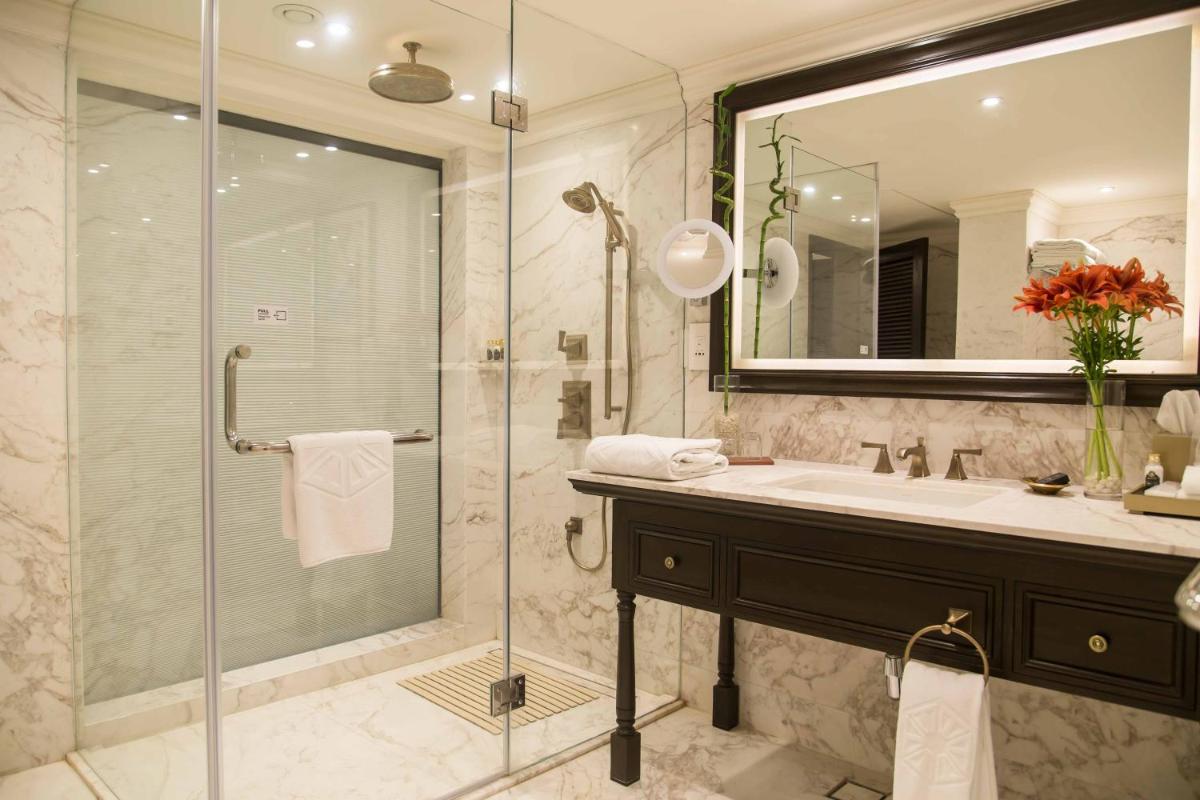 a bathroom with a shower and a sink and a mirror at Taj Bengal in Kolkata