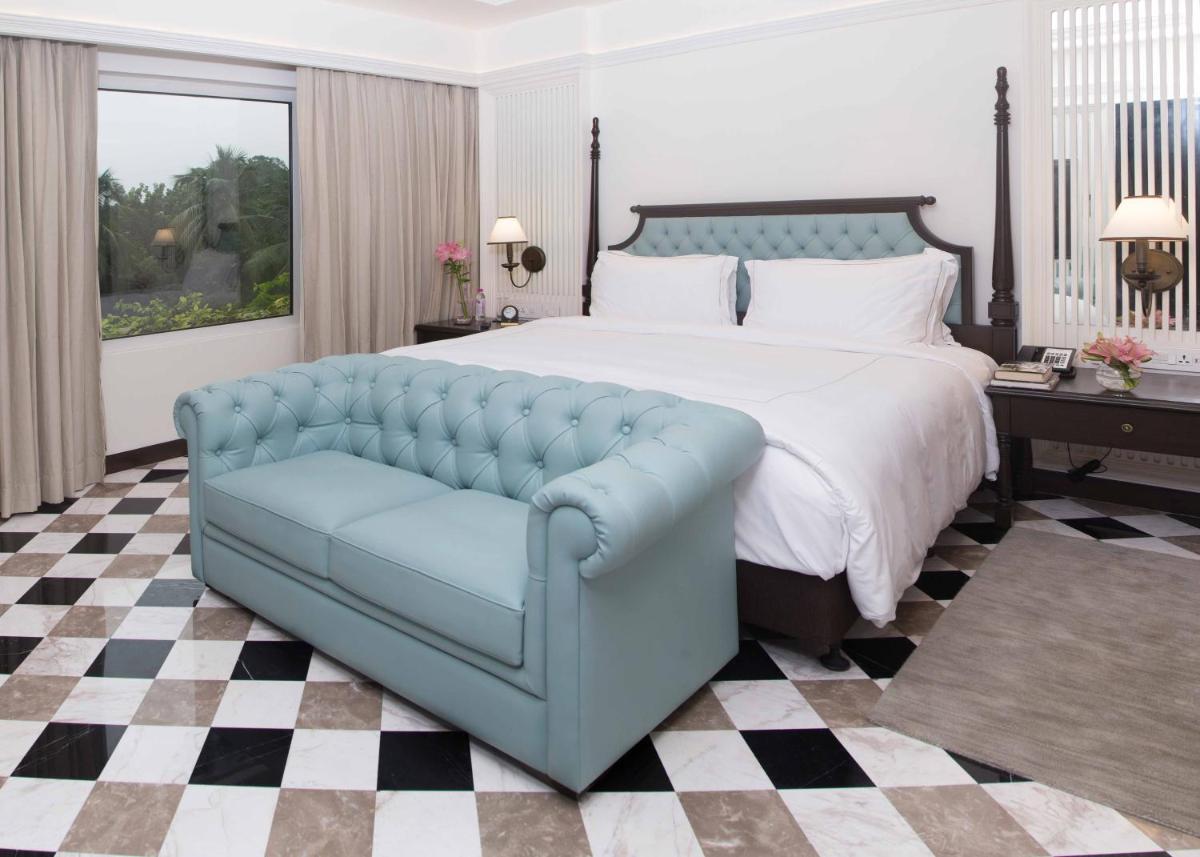 a bedroom with a large bed and a blue couch at Taj Bengal in Kolkata