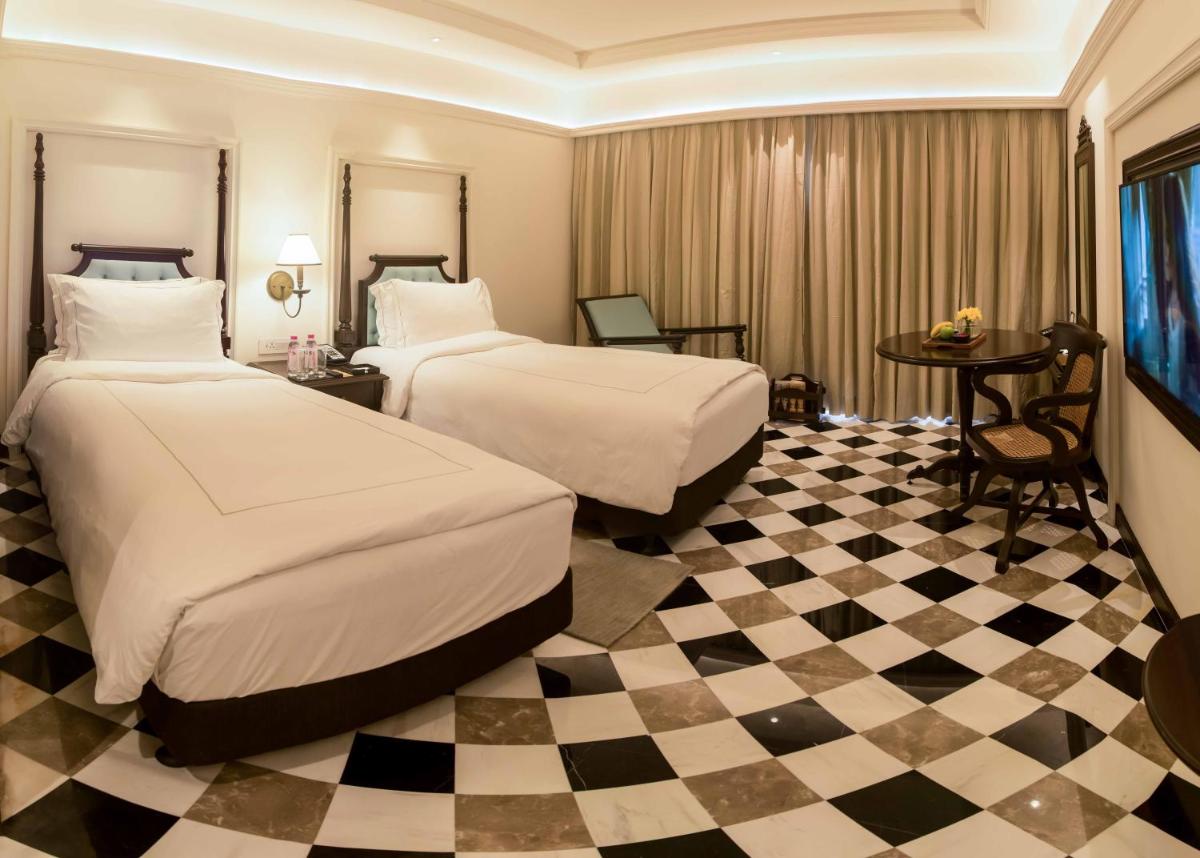 a hotel room with two beds and a checkered floor at Taj Bengal in Kolkata