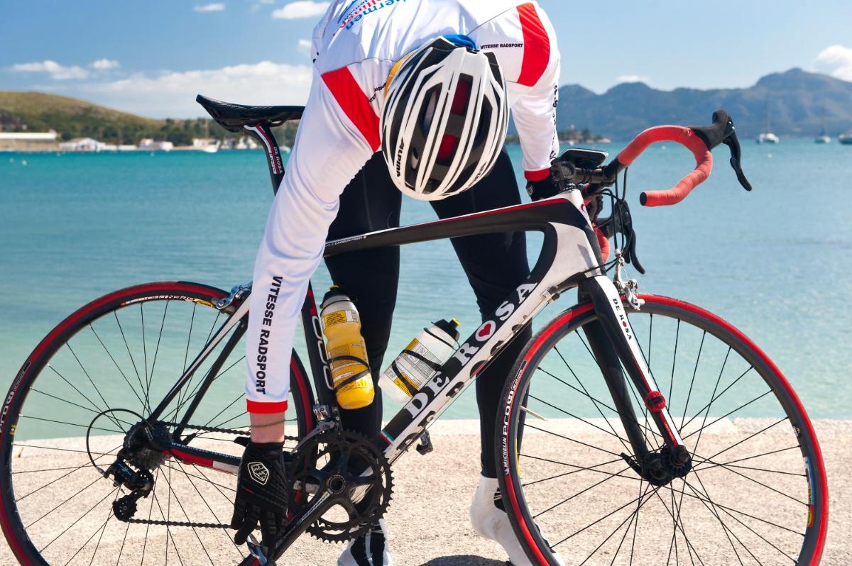 un hombre está montando una bicicleta en la playa en Alcudia Garden Aparthotel, en Puerto de Alcudia