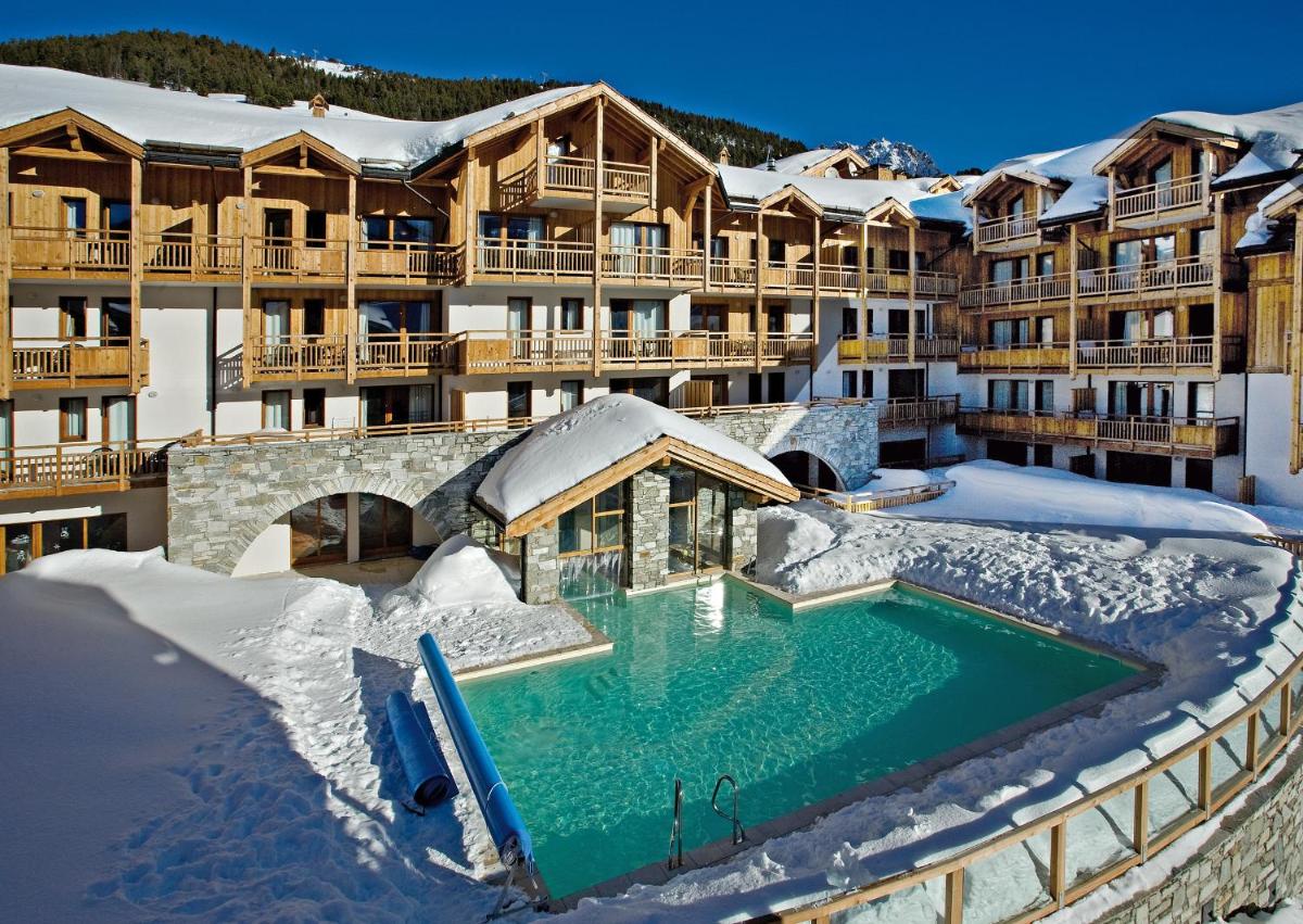 un complexe avec une piscine dans la neige dans l'établissement Résidence Club mmv Le Hameau des Airelles ****, à Montgenèvre