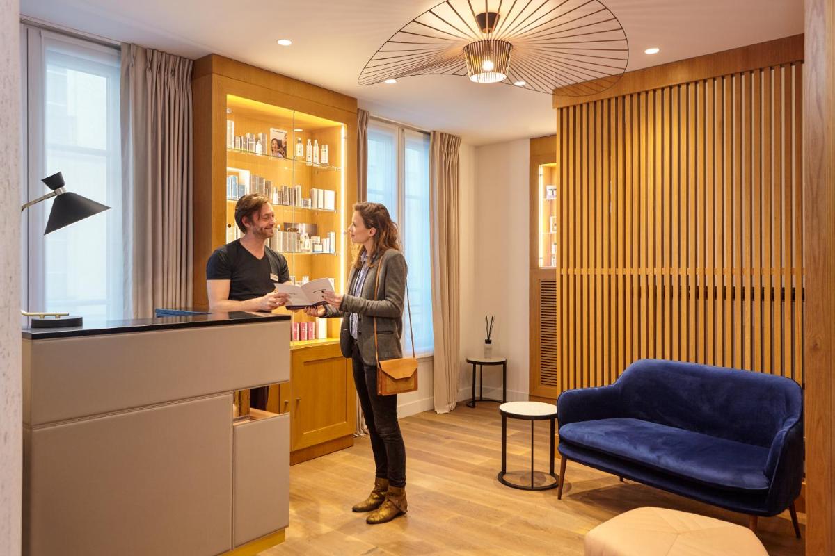 un homme et une femme debout à un comptoir dans l'établissement Mercure Paris Opera Garnier Hôtel & Spa, à Paris