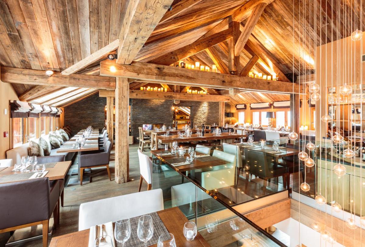 un restaurant avec des plafonds en bois, des tables et des chaises dans l'établissement Hotel Le Savoy, à Méribel