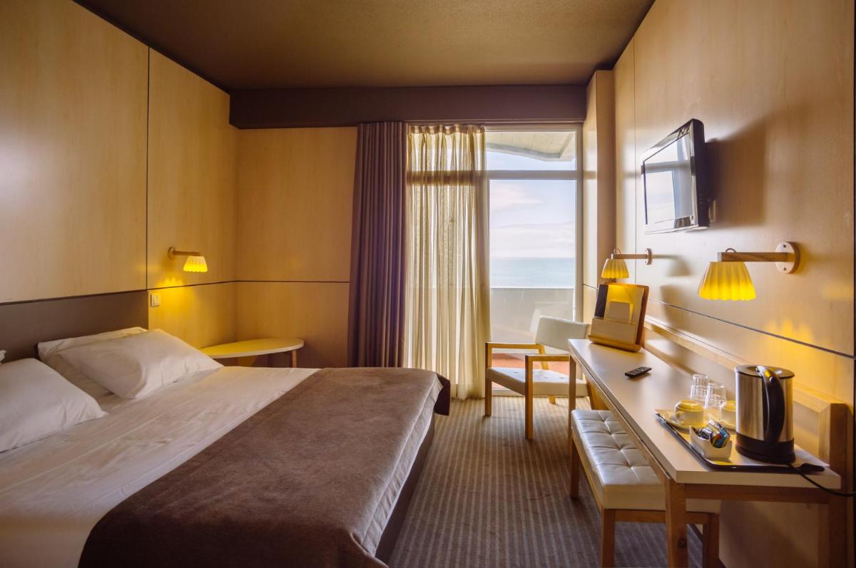 um quarto de hotel com uma cama, uma escrivaninha e uma janela em Axis Vermar Conference & Beach Hotel na Póvoa do Varzim