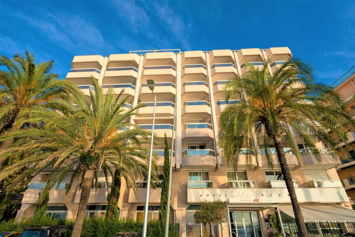 un bâtiment avec des palmiers devant dans l'établissement Hôtel Riva Art & Spa, à Menton
