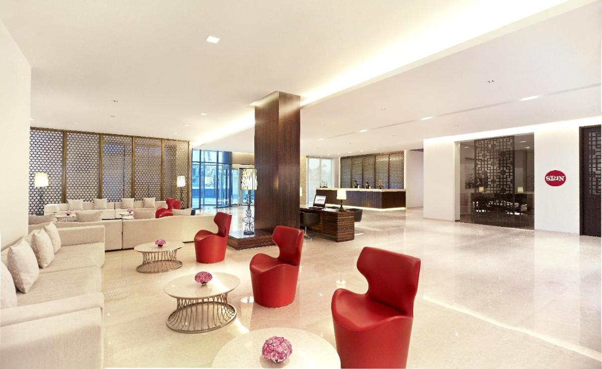 a large living room with red chairs and couches at Vivanta Chennai IT Expressway OMR in Chennai