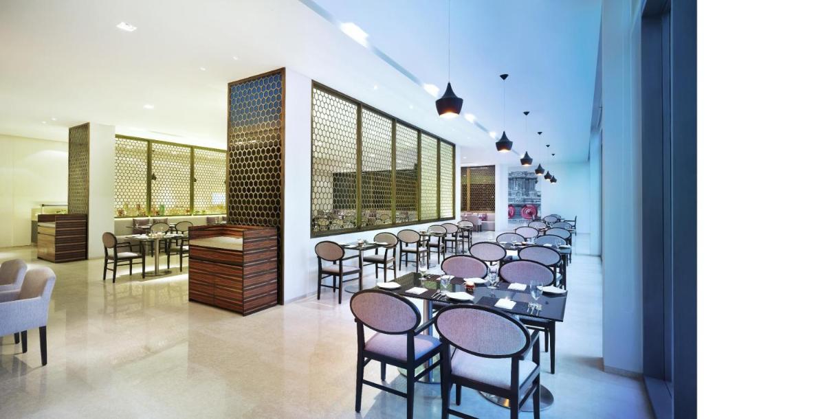 a restaurant with a row of tables and chairs at Vivanta Chennai IT Expressway OMR in Chennai