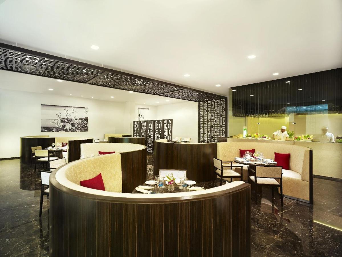 a restaurant with tables and chairs and a bar at Vivanta Chennai IT Expressway OMR in Chennai