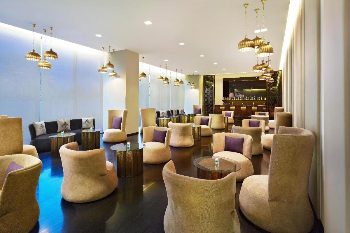 a waiting room with chairs and tables and a bar at Vivanta Chennai IT Expressway OMR in Chennai