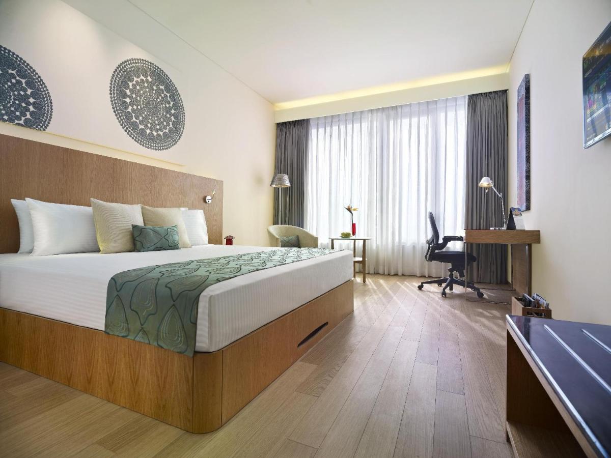 a hotel room with a large bed and a desk at Vivanta Chennai IT Expressway OMR in Chennai