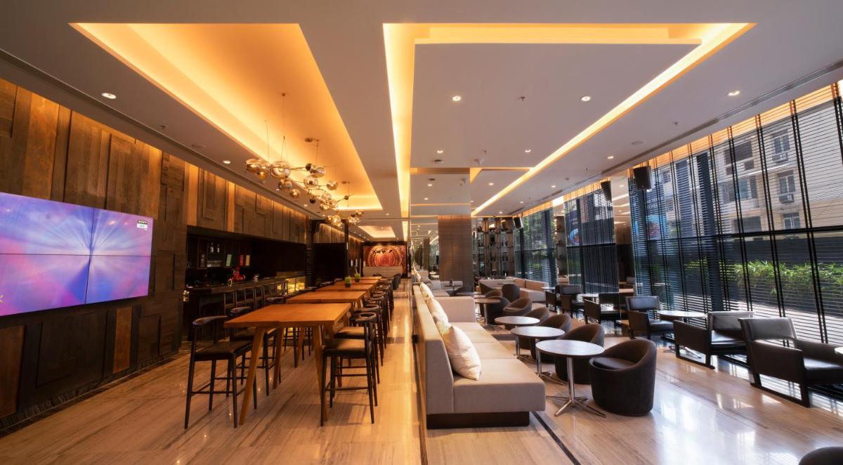 a restaurant with a bar with tables and chairs at Novotel Chennai Chamiers Road in Chennai