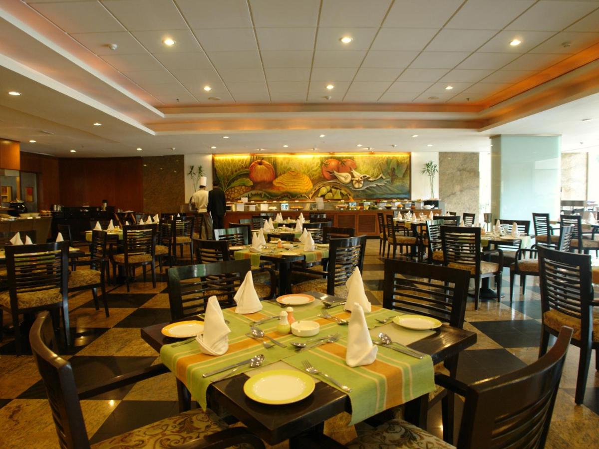 a dining room with tables and chairs in a restaurant at The Lalit Ashok in Bengaluru a dining room with tables and chairs in a restaurant at The Lalit Ashok in Bengaluru