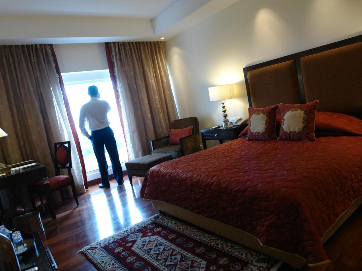 a man standing in a hotel room looking out the window at The Lalit Ashok in Bengaluru a man standing in a hotel room looking out the window at The Lalit Ashok in Bengaluru