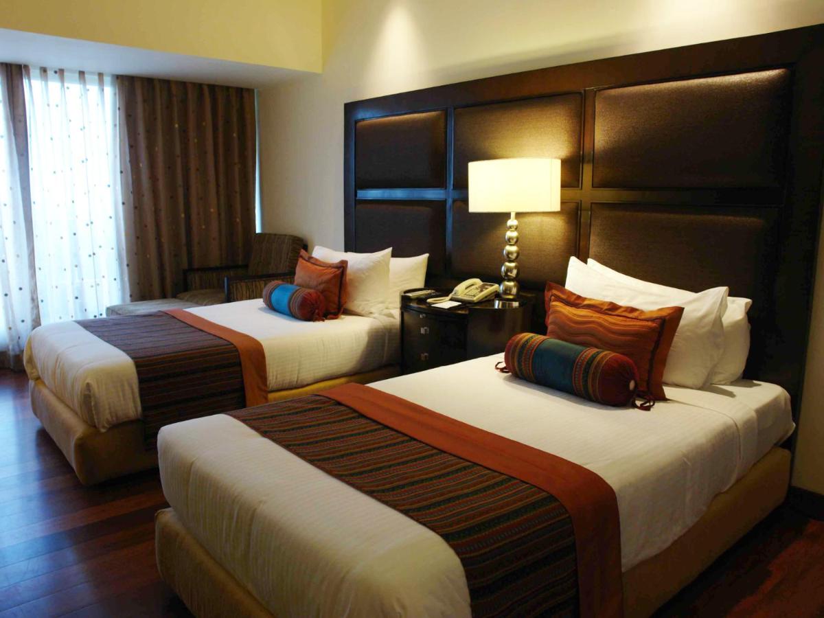 a hotel room with two beds and a lamp at The Lalit Ashok in Bengaluru a hotel room with two beds and a lamp at The Lalit Ashok in Bengaluru