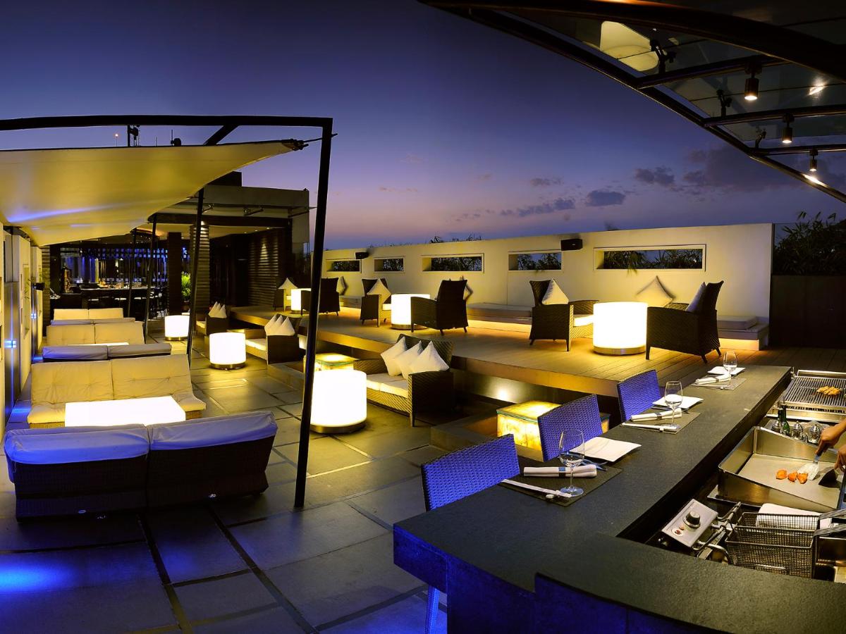a rooftop patio with chairs and tables and lights at The Lalit Ashok in Bengaluru a rooftop patio with chairs and tables and lights at The Lalit Ashok in Bengaluru