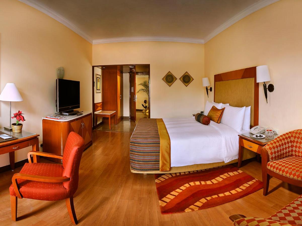 a hotel room with a bed and a television at The Lalit Ashok in Bengaluru a hotel room with a bed and a television at The Lalit Ashok in Bengaluru
