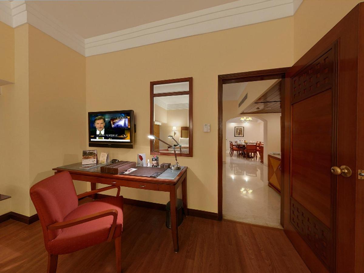 a room with a desk and a chair and a mirror at The Lalit Ashok in Bengaluru a room with a desk and a chair and a mirror at The Lalit Ashok in Bengaluru