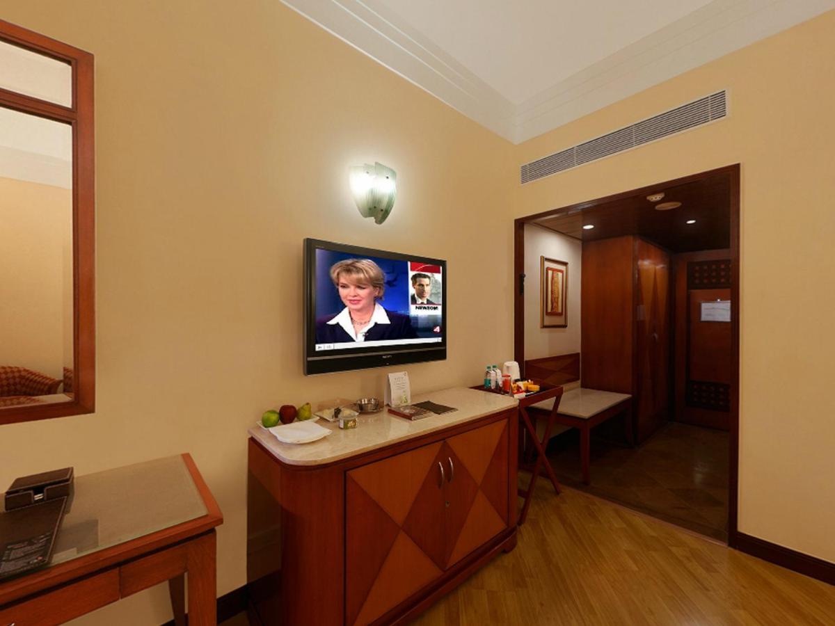 a hospital room with a tv on the wall at The Lalit Ashok in Bengaluru a hospital room with a tv on the wall at The Lalit Ashok in Bengaluru