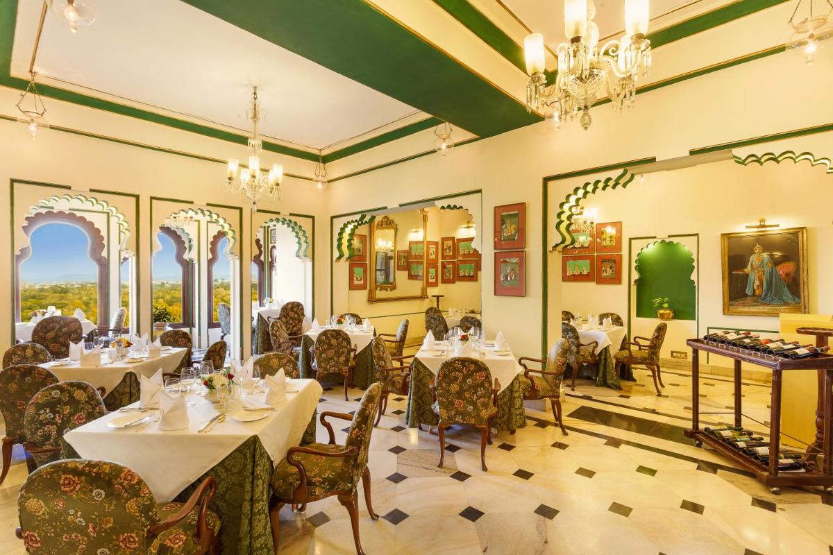 a dining room with tables and chairs and chandeliers at Shiv Niwas Palace by HRH Group of Hotels in Udaipur