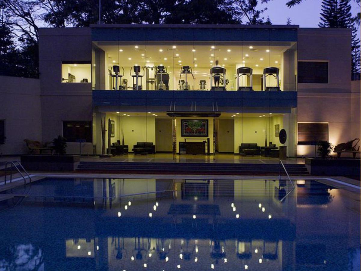 a large house with a swimming pool in front of it at The Lalit Ashok in Bengaluru a large house with a swimming pool in front of it at The Lalit Ashok in Bengaluru