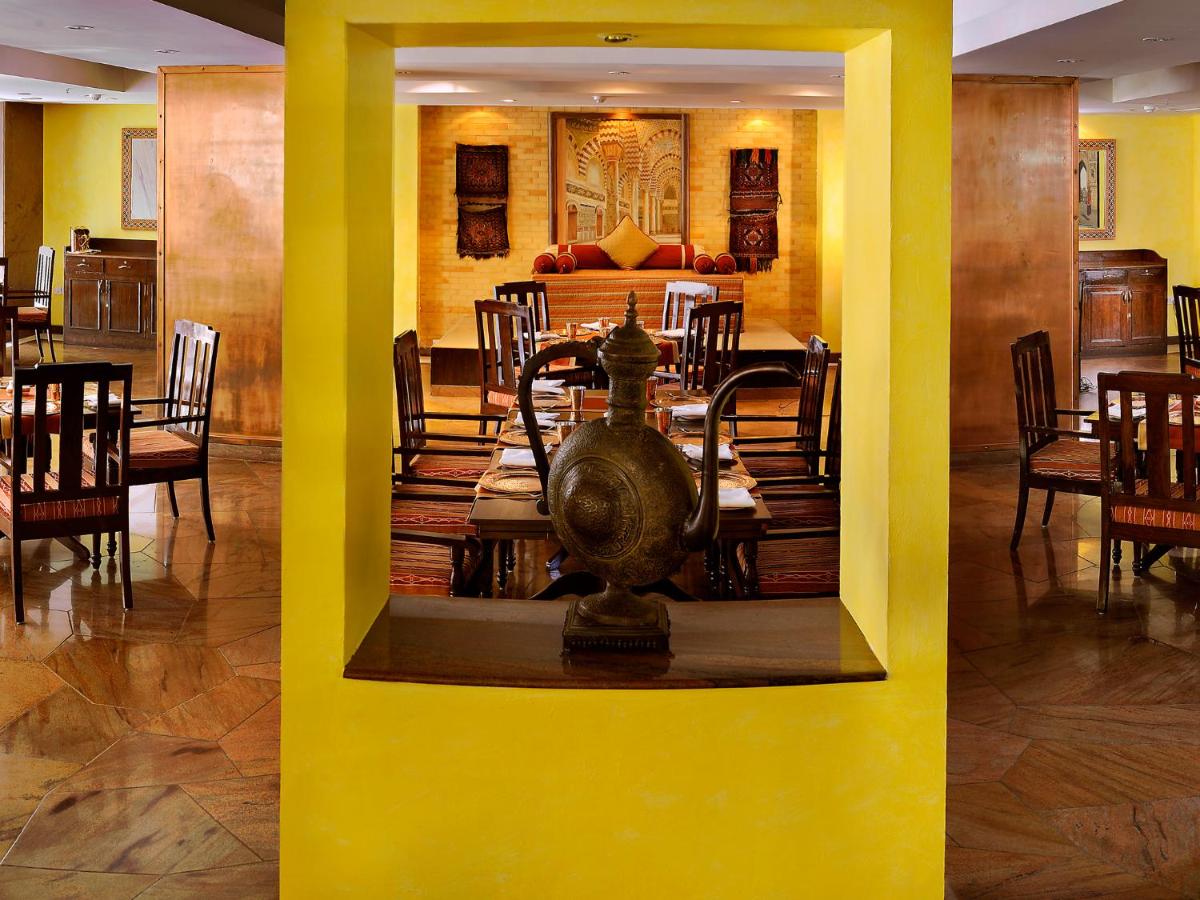 a dining room with yellow walls and a table and chairs at The Lalit Ashok in Bengaluru a dining room with yellow walls and a table and chairs at The Lalit Ashok in Bengaluru