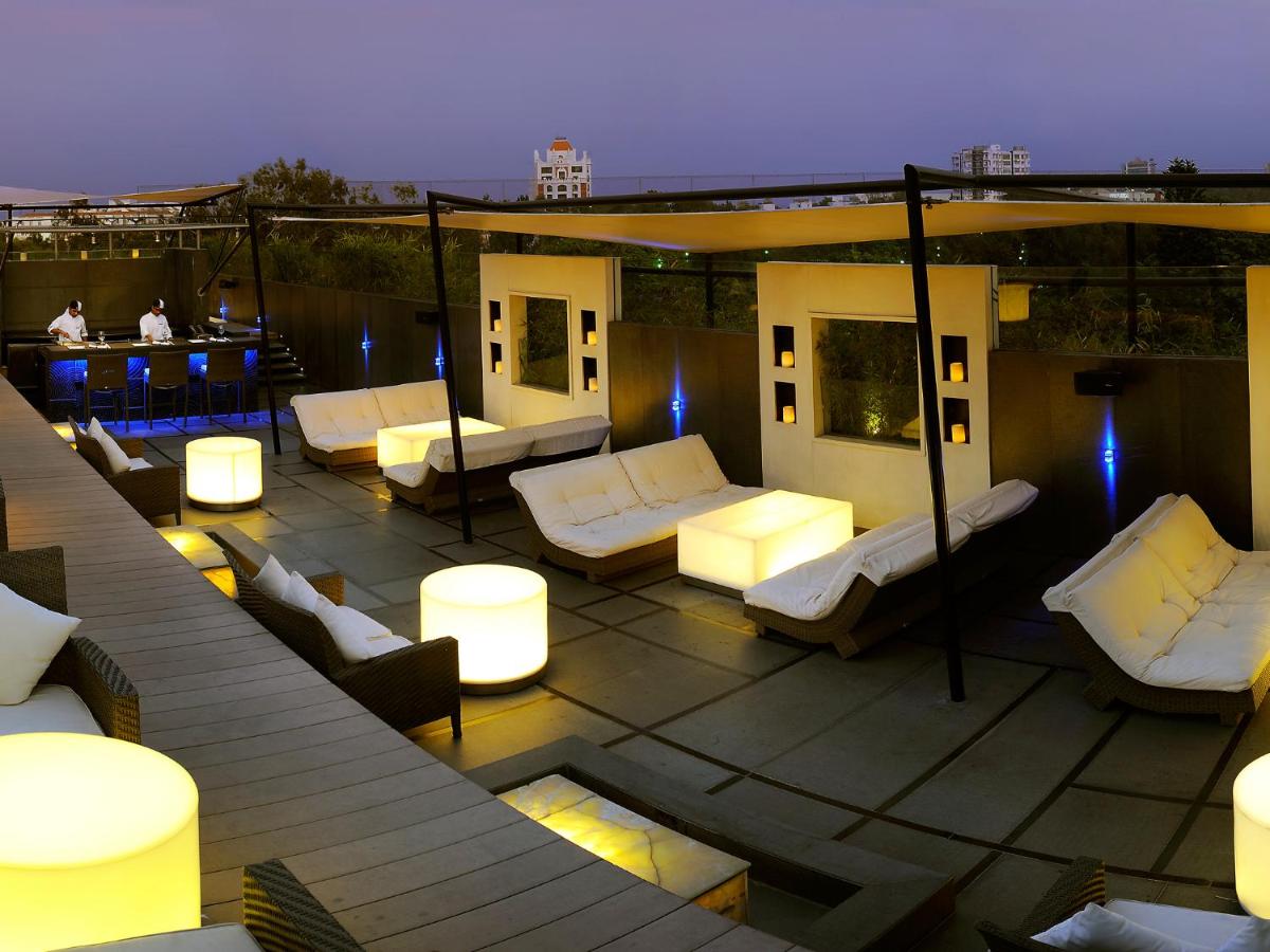 a rooftop patio with white couches and a bar at The Lalit Ashok in Bengaluru a rooftop patio with white couches and a bar at The Lalit Ashok in Bengaluru