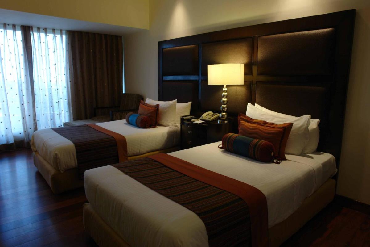 a hotel room with two beds and a lamp at The Lalit Ashok in Bengaluru a hotel room with two beds and a lamp at The Lalit Ashok in Bengaluru