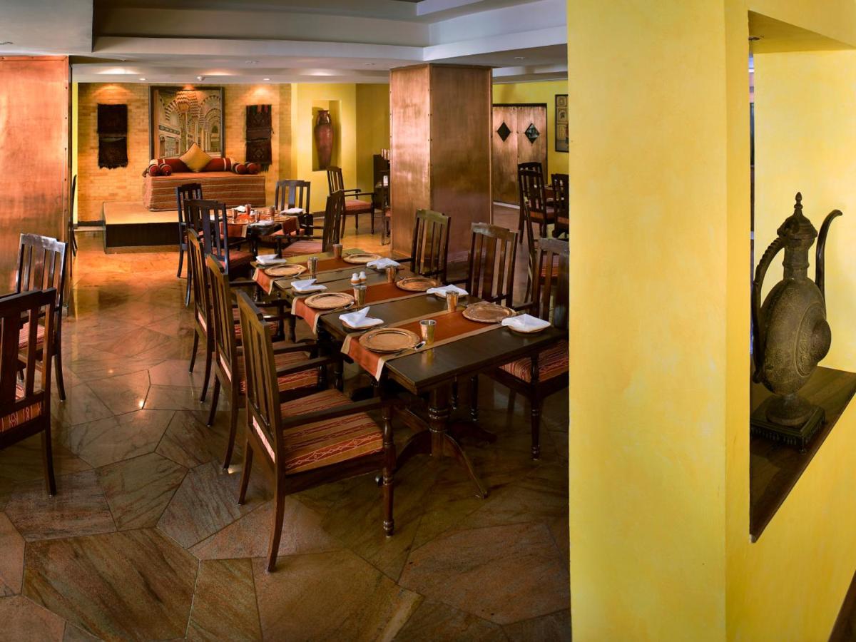 a dining room with a long table and chairs at The Lalit Ashok in Bengaluru a dining room with a long table and chairs at The Lalit Ashok in Bengaluru