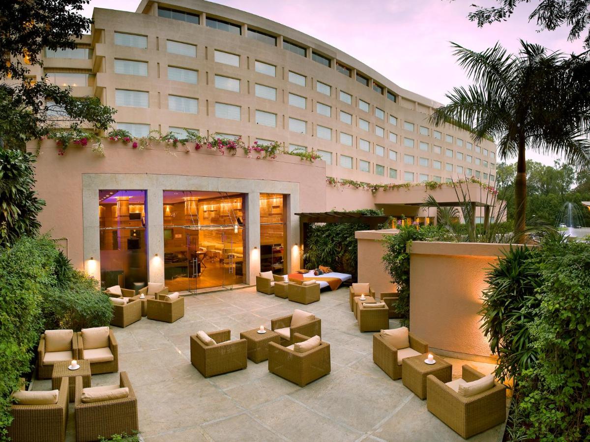 a hotel courtyard with couches and chairs in front of a building at The Lalit Ashok in Bengaluru a hotel courtyard with couches and chairs in front of a building at The Lalit Ashok in Bengaluru