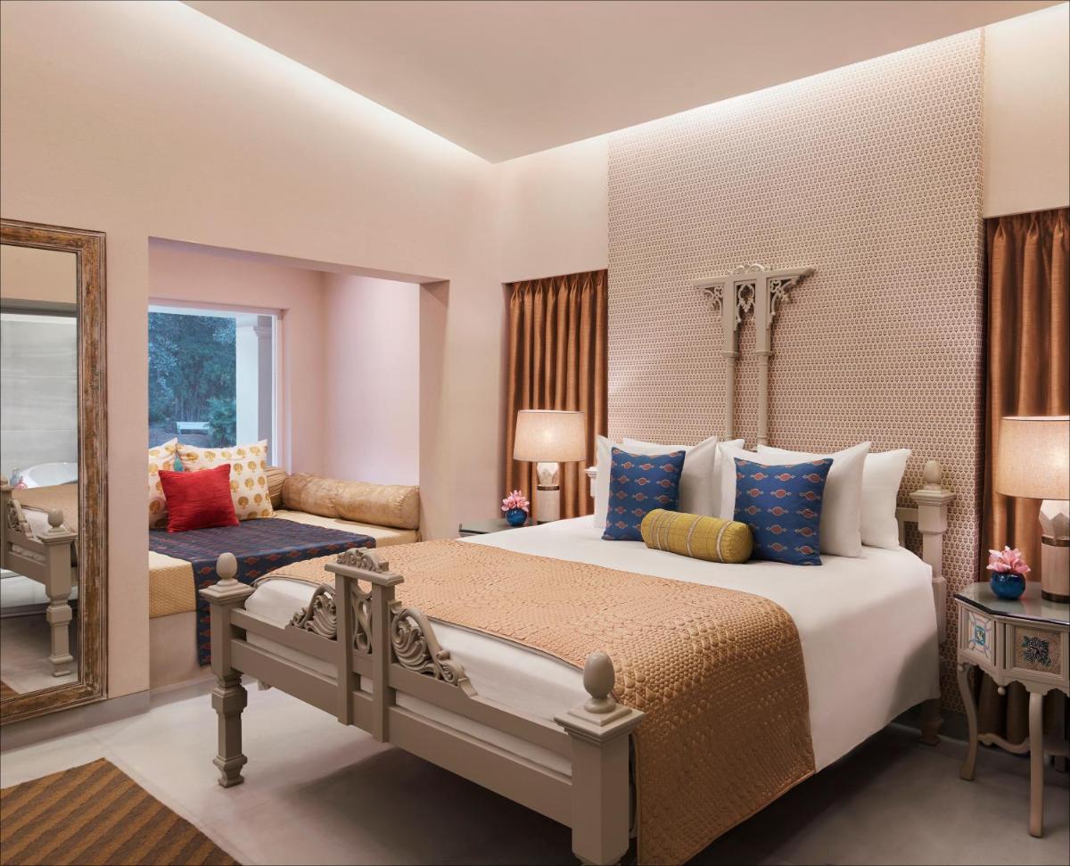 a bedroom with a large bed and a mirror at Taj Aravali Resort & Spa Udaipur in Udaipur