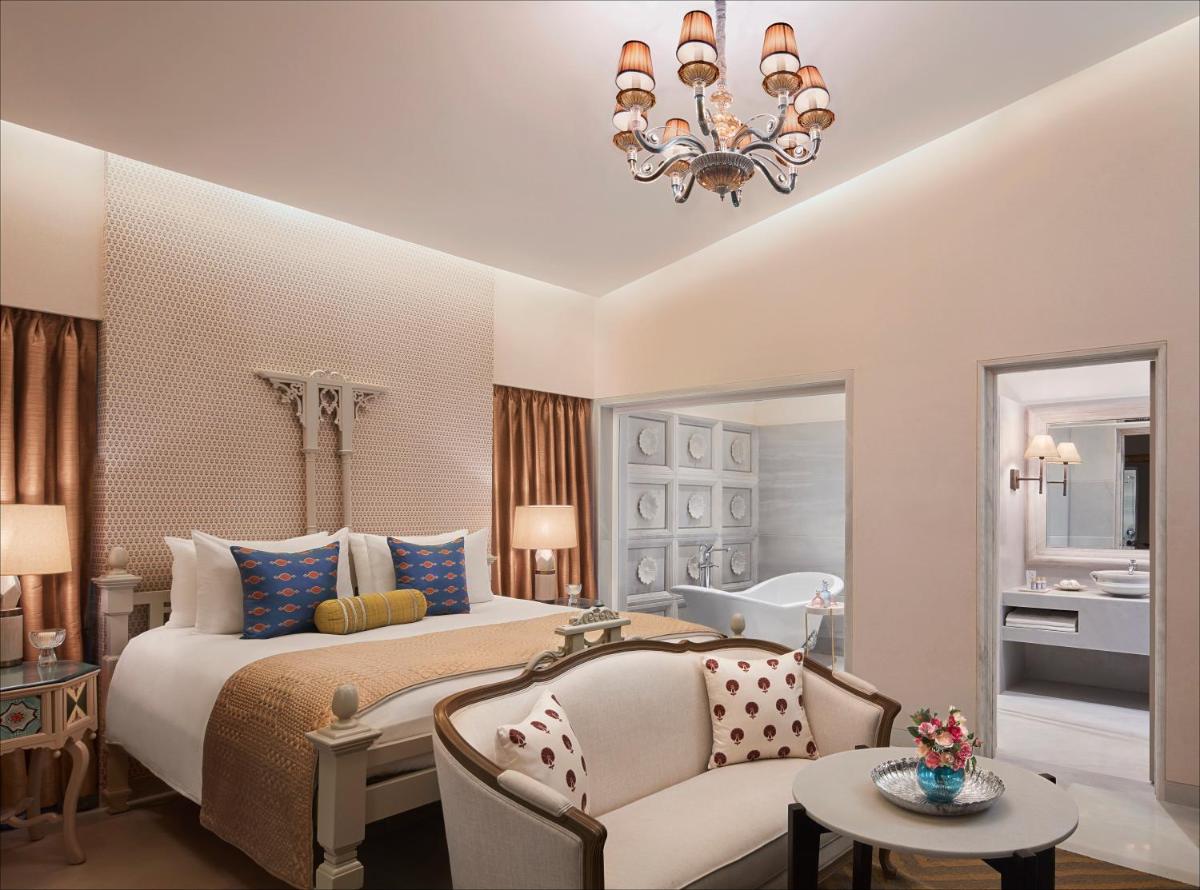 a bedroom with a bed and a couch and a chandelier at Taj Aravali Resort & Spa Udaipur in Udaipur