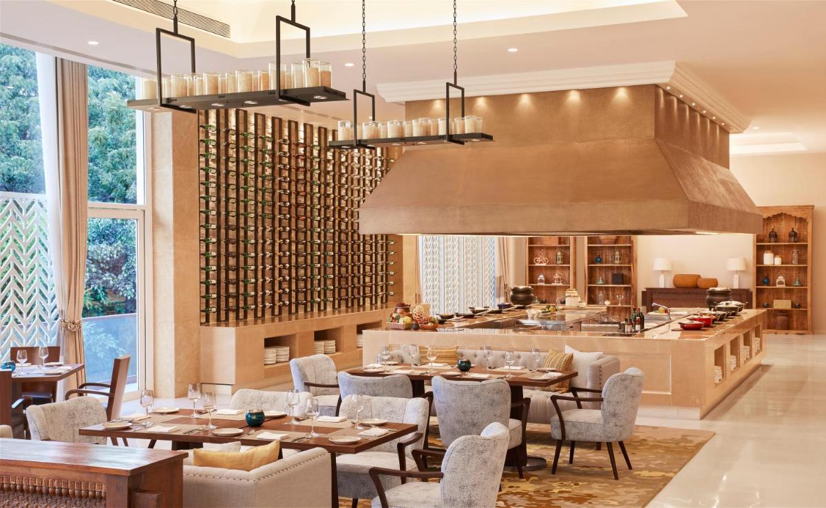 a restaurant with tables and chairs and a kitchen at Taj Aravali Resort & Spa Udaipur in Udaipur