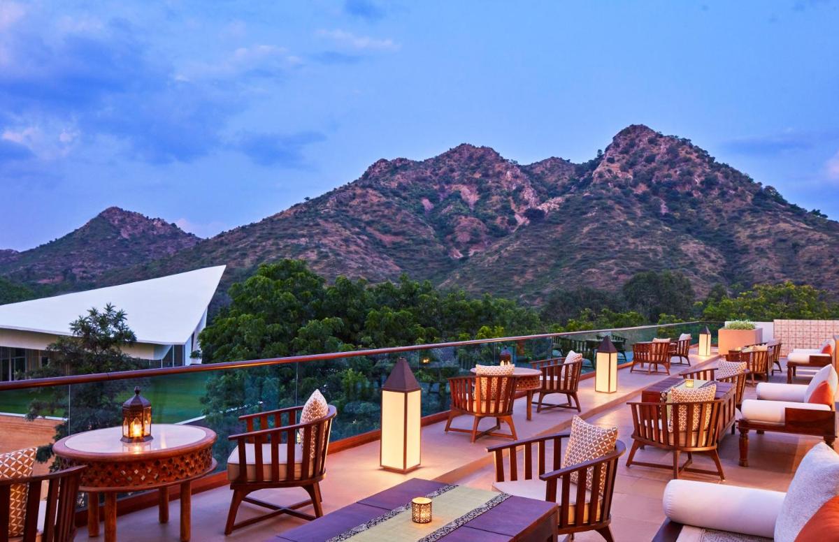 a patio with tables and chairs with a mountain in the background at Taj Aravali Resort & Spa Udaipur in Udaipur