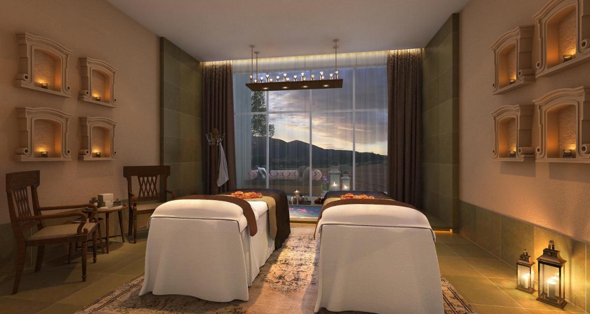 a room with two beds and a table and a window at Taj Aravali Resort & Spa Udaipur in Udaipur