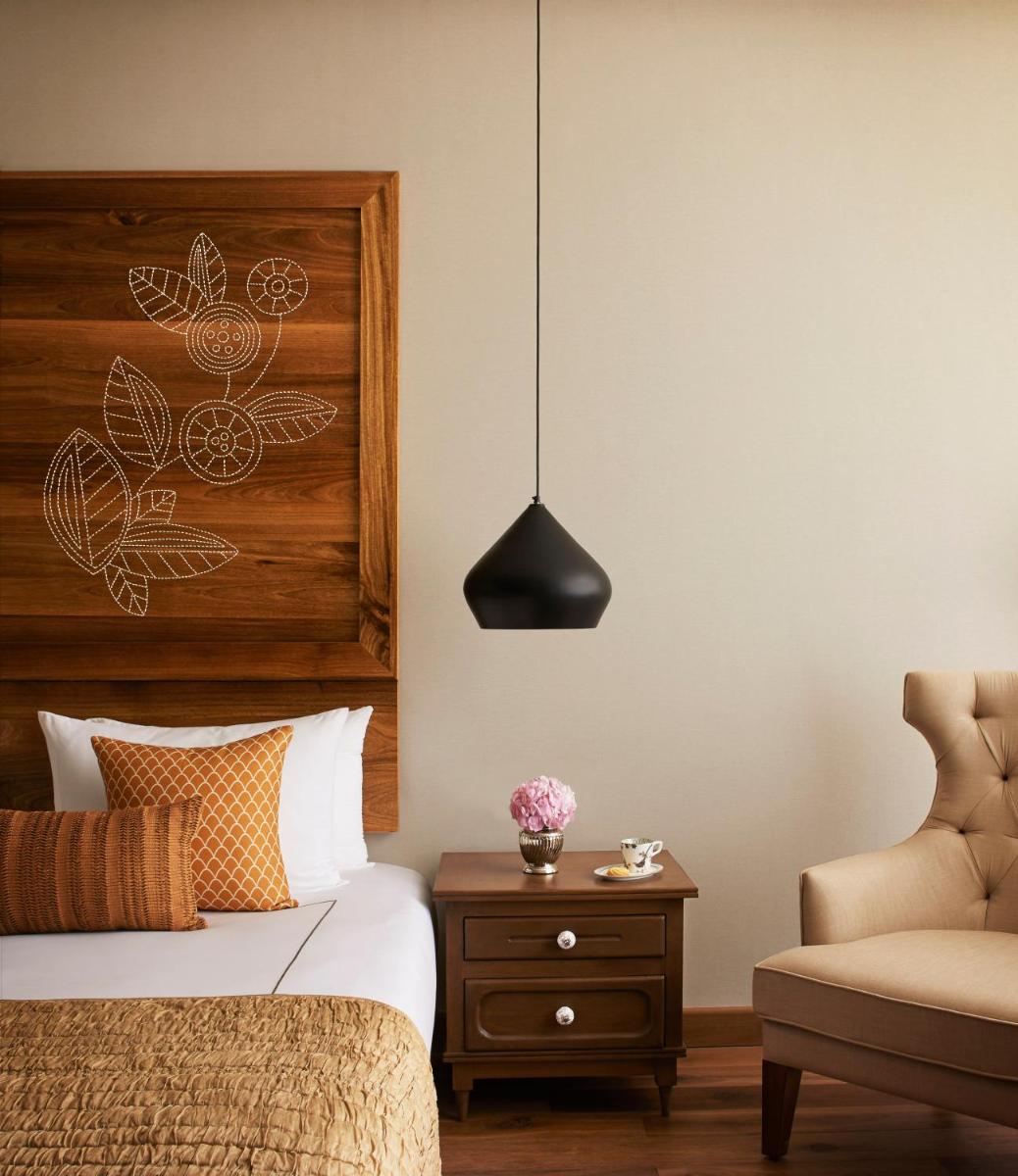 a bedroom with a bed and a chair at Taj Aravali Resort & Spa Udaipur in Udaipur