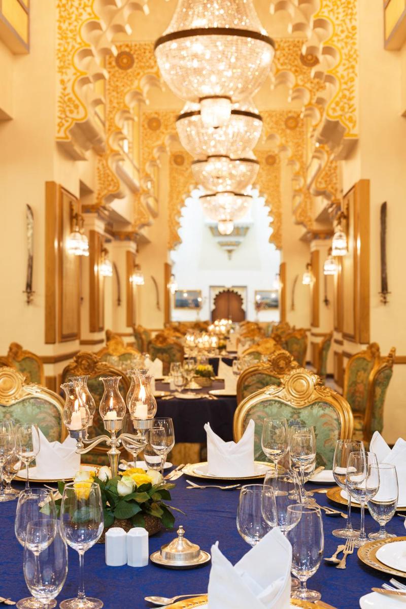 a dining room with a long table with wine glasses at Taj Fateh Prakash Palace Udaipur in Udaipur