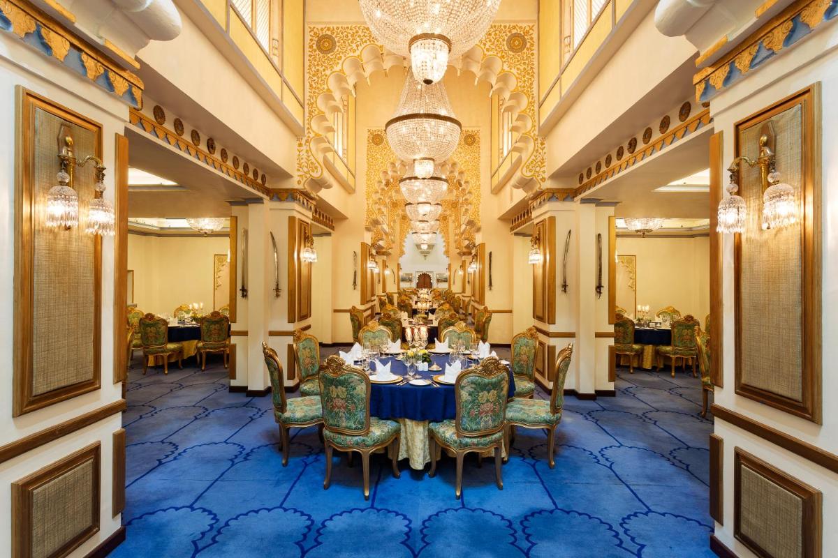 a dining room with a table and chairs and a chandelier at Taj Fateh Prakash Palace Udaipur in Udaipur