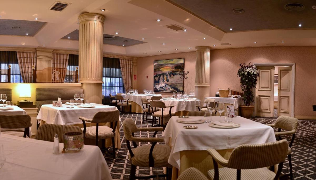 Un restaurante con mesas y sillas con mantel blanco. en Beatriz Toledo Auditorium & Spa, en Toledo