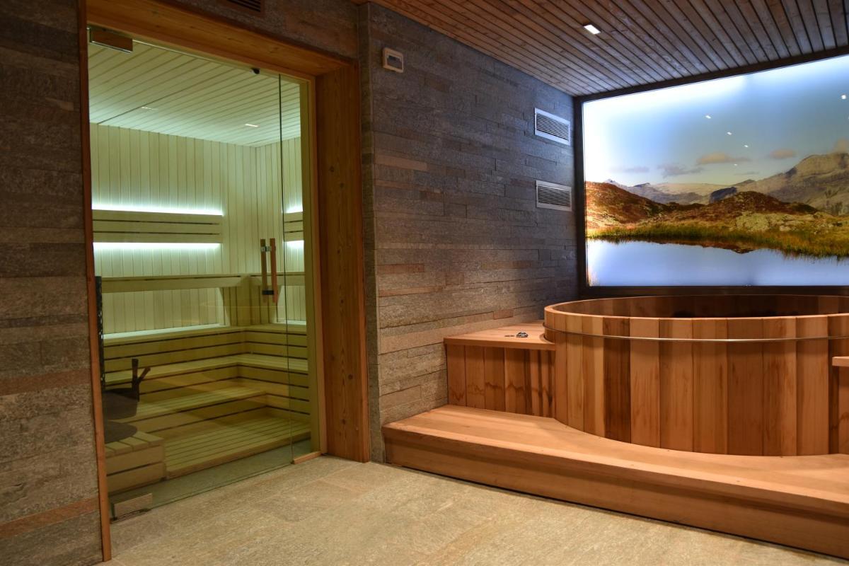 La salle de bains est pourvue d'une douche et d'une grande télévision murale. dans l'établissement Hôtel LAPIAZ & Spa - FLAINE, à Flaine