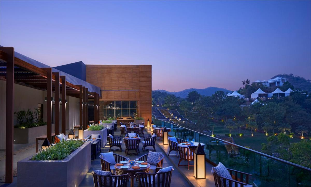 a restaurant with tables and chairs on a balcony at Taj Aravali Resort & Spa Udaipur in Udaipur