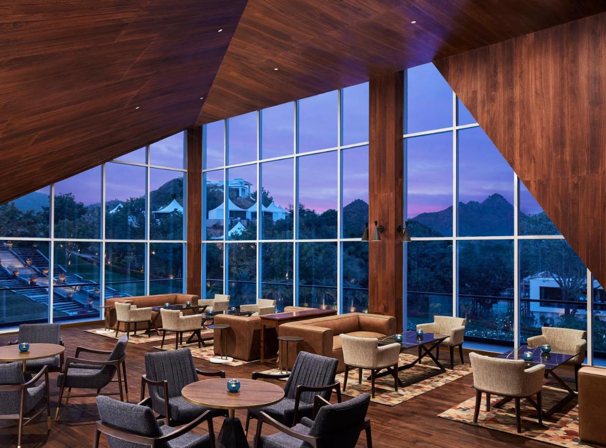 a restaurant with tables and chairs and large windows at Taj Aravali Resort & Spa Udaipur in Udaipur