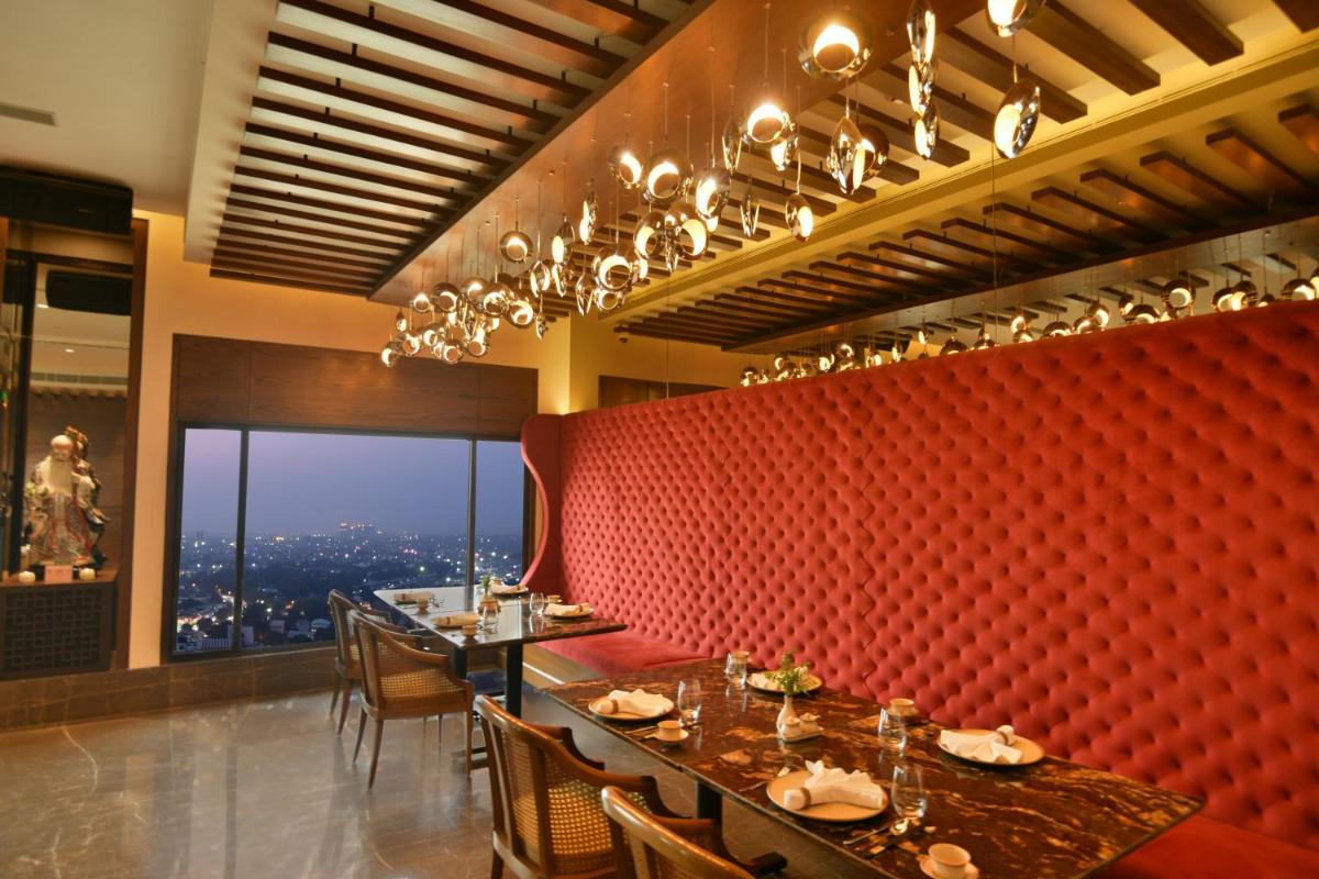 a restaurant with tables and chairs and a red wall at The LaLiT New Delhi in New Delhi