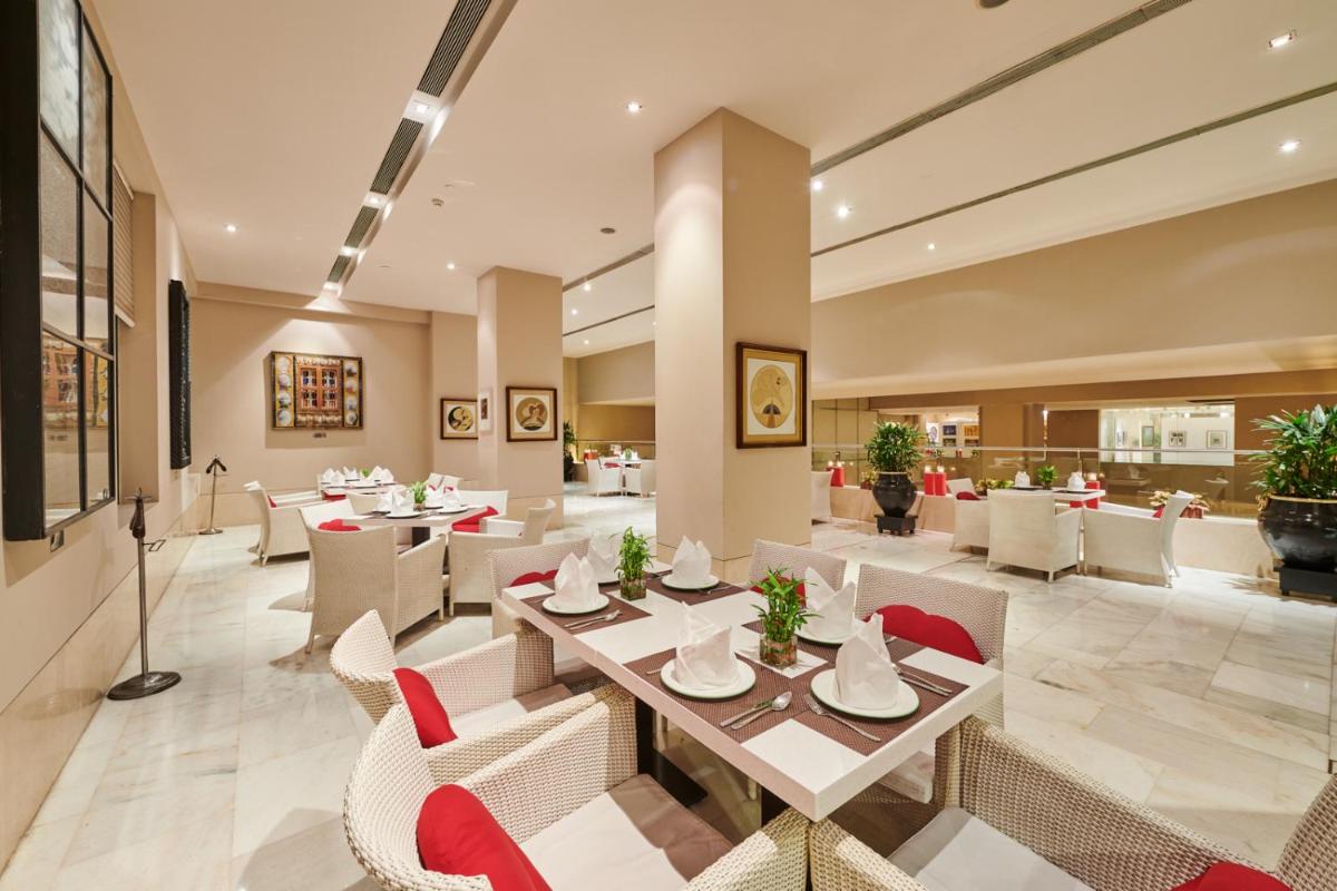 a dining room with tables and chairs and tablesktop at The LaLiT New Delhi in New Delhi
