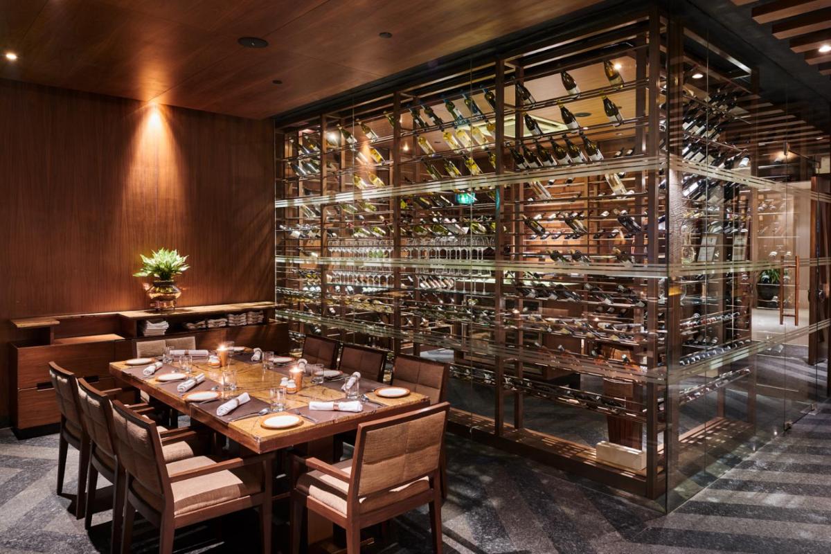a dining room with a table and a wall of wine bottles at The LaLiT New Delhi in New Delhi