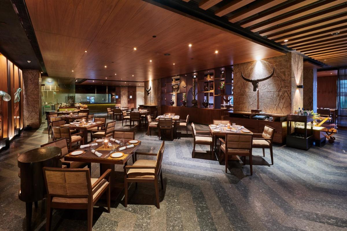 a dining room with wooden tables and chairs at The LaLiT New Delhi in New Delhi
