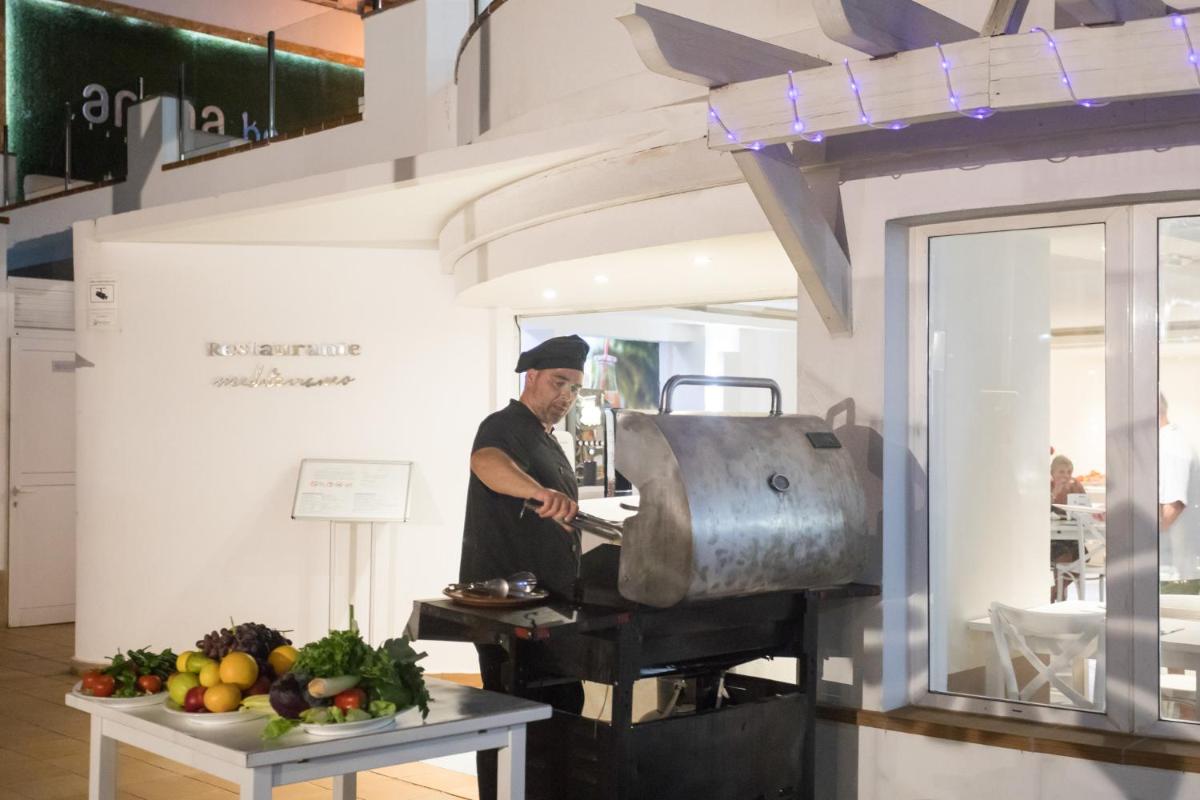 un hombre preparando comida en una cocina con parrilla en Hotel Arena Beach, en Corralejo 47 fotos más