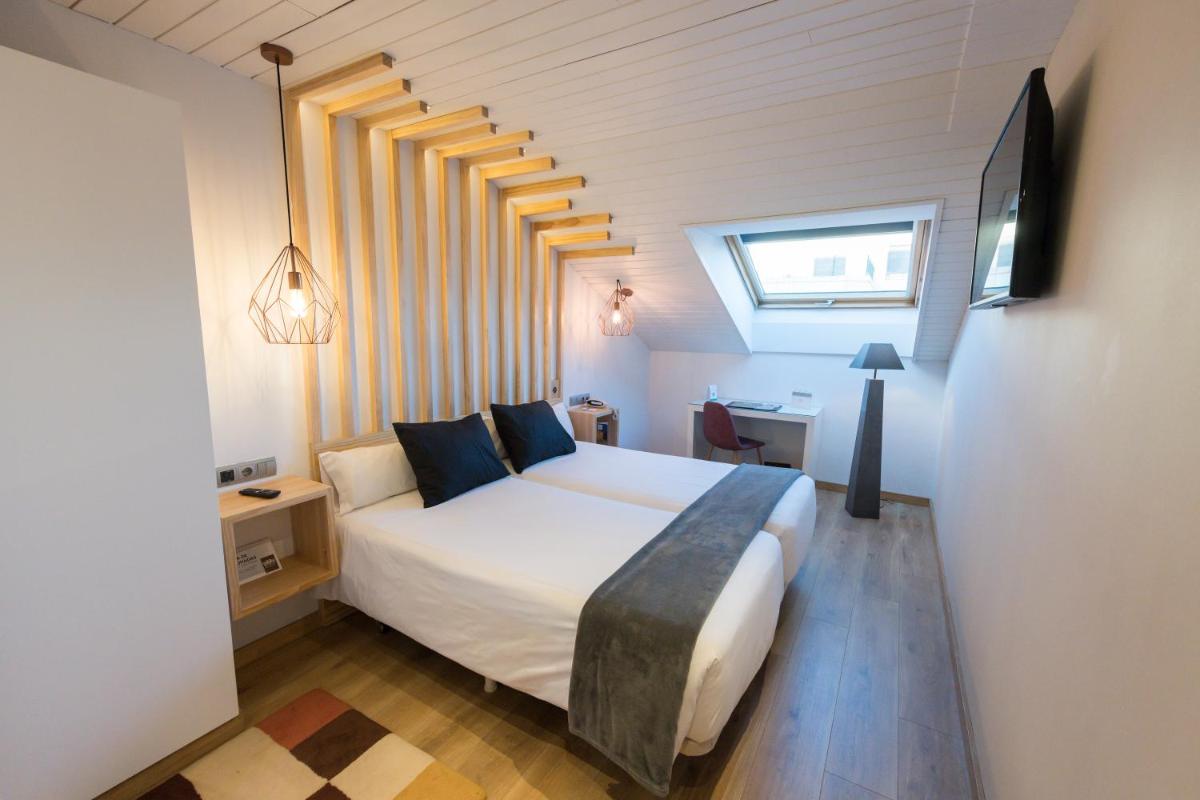 Un dormitorio con una gran cama blanca con almohadas azules. en Hotel Fruela, en Oviedo