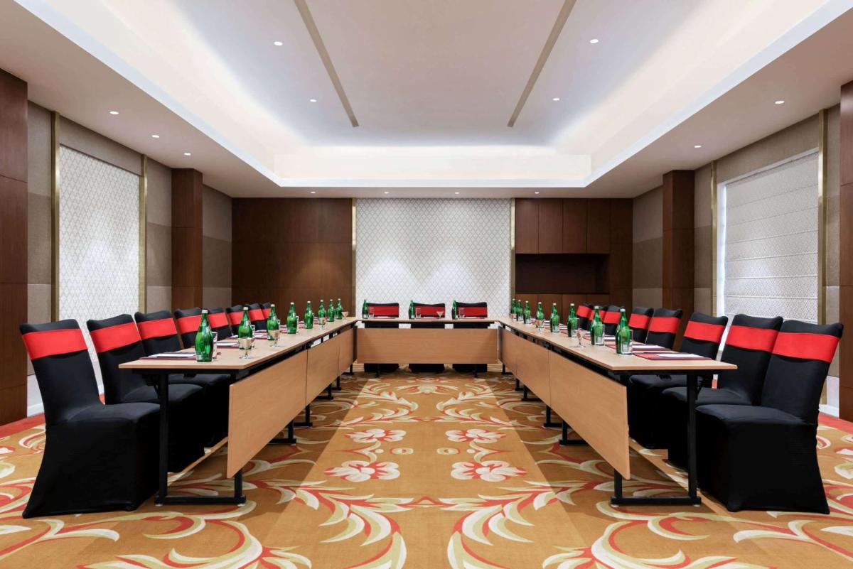 a conference room with long tables and chairs at Ramada by Wyndham Lucknow Hotel and Convention Center in Lucknow