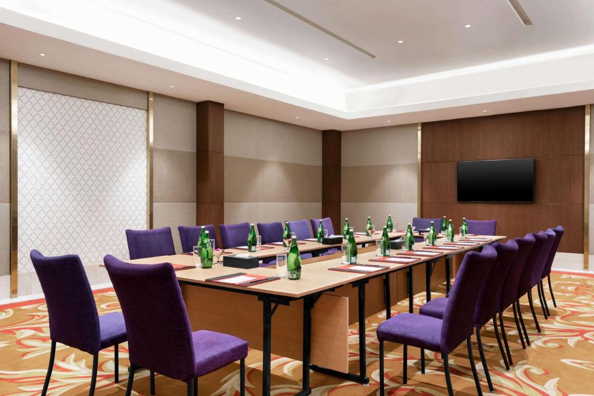 a conference room with a long table and purple chairs at Ramada by Wyndham Lucknow Hotel and Convention Center in Lucknow