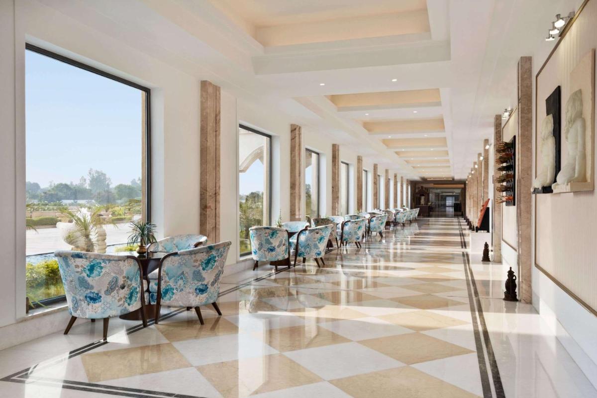 a long corridor with chairs and tables and windows at Ramada by Wyndham Lucknow Hotel and Convention Center in Lucknow